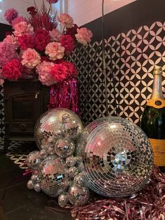 some disco balls are sitting on the floor next to a vase with pink flowers in it