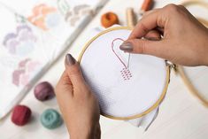 a woman is stitching a heart on a piece of fabric