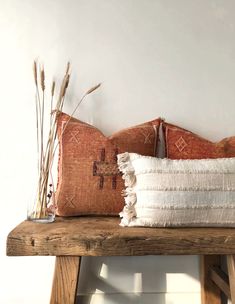 two decorative pillows on a wooden bench