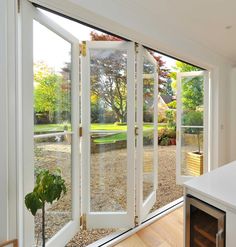 an open patio door leading to a back yard with trees and bushes in the background