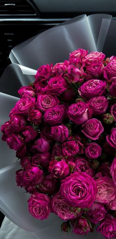 a large bouquet of purple roses in a white vase