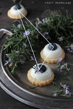 three small cookies with blueberries and lavender sprigs on a metal platter