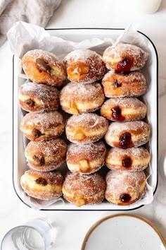 powdered doughnuts in a box with jam on top