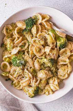 a bowl filled with pasta and broccoli on top of a white table cloth