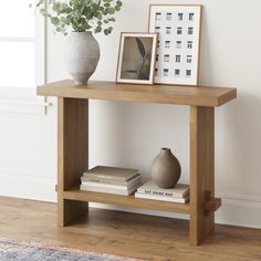 a wooden table topped with books next to a vase and framed photograph on top of it