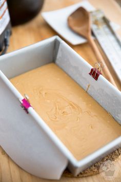 a pan filled with batter sitting on top of a wooden table next to utensils