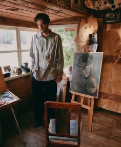 a man standing next to an easel in a room