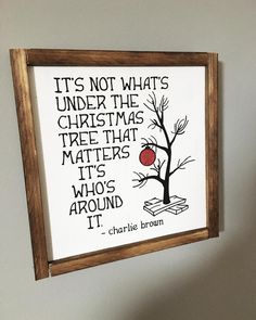 a wooden frame with a quote on it that reads, it's not what's under the christmas tree that matters who's around it