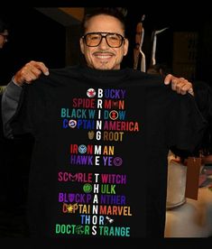 a man holding up a black shirt with the names of his favorite characters on it