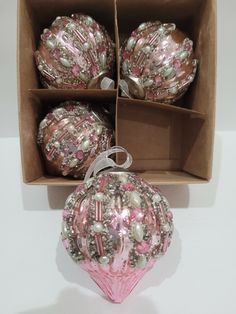 three pink ornaments in a box on a table