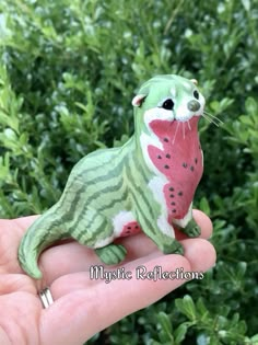 a hand holding a small green and pink animal