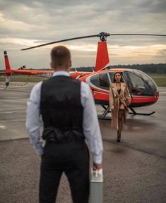 a man and woman walking towards a helicopter