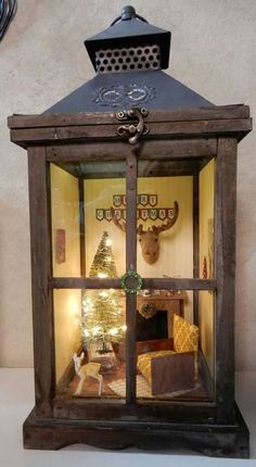 a christmas display in a glass case with a deer head on the wall behind it