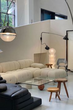 a living room filled with lots of furniture next to a tall ceiling mounted light fixture