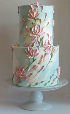 a three tiered cake with pink flowers on it's side and blue icing