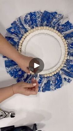 someone is making a blue and white flower wreath with beaded trim on the edge