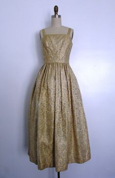 This vintage late 1950s to early 1960s gold damask party dress is gorgeous! This dress is sleeveless, has a square neckline, a cinched waist, the gold damask fabric has a subtle decorative raised floral print, there's a tulle underskirt and a hidden back zipper. Simply feminine and heavenly. A great holiday evening party dress. Effortless and oh so pretty! Pair with a great pair of gold or black shoes and evening bag. Perfect for a formal holiday party. ------------------------------------------ Gold Brocade Dress For Gala, Gold Dress With Pleated Bodice For Wedding, Gold Wedding Dress With Pleated Bodice, Formal Gold Brocade Dress, Vintage Dress With Pleated Bodice For Gala, Vintage Brocade Party Dress, Vintage Gold Dress For Evening, Vintage Gold Dresses For Evening, Vintage Gold Evening Dress