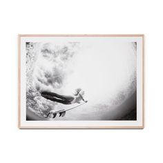 a black and white photo of a person on a surfboard in the water with clouds behind them