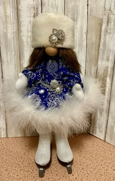 a stuffed animal wearing a blue and white dress with fur on it's head