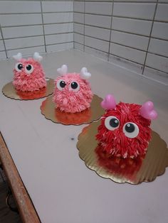 three cakes decorated to look like monsters with eyes and horns on them sitting on a counter