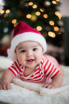 a baby wearing a santa hat on top of a blanket