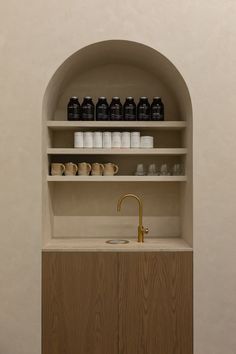 an arch - shaped shelf with jars and cups on it is next to a sink