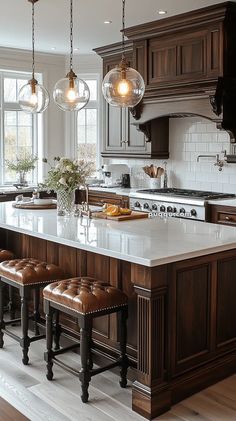 a kitchen island with stools and lights hanging from it's ceiling over the counter