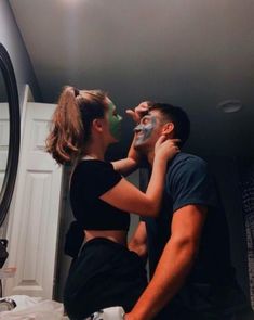 a man and woman are in the bathroom with their faces covered by masks while they look into each other's eyes