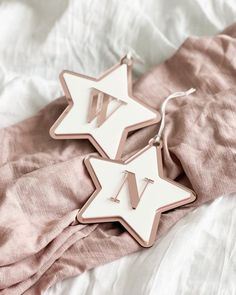 two white and pink star shaped earrings laying on top of a bed next to each other