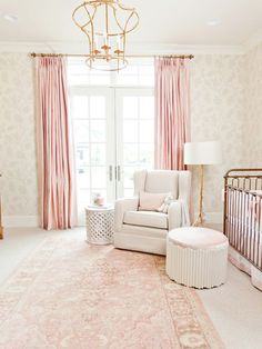 a room with pink curtains, a chair and a baby crib in the corner