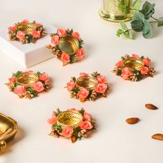 several pieces of jewelry sitting next to each other on a white surface with flowers and leaves