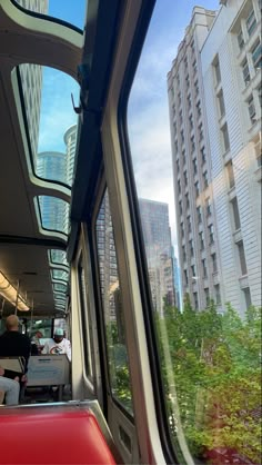 the inside of a train with people sitting on it and buildings in the background at daytime