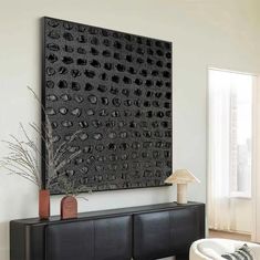 a living room with a large black art piece on the wall