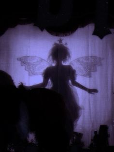 the silhouette of a woman standing in front of a curtain