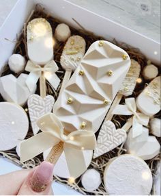 a box filled with lots of white chocolates next to a person's hand