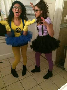 two women dressed in costumes standing next to each other on a tiled floored bathroom