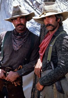 two men wearing hats and standing next to each other