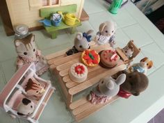 several toy animals sitting around a table with cupcakes and donuts on it