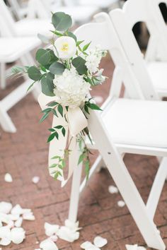 a bouquet of flowers sitting on top of a white folding chair with petals scattered around it