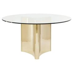 a glass and brass dining table with an oval shaped design on the top, against a white background