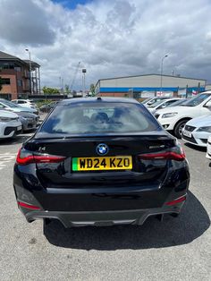 the back end of a black bmw car parked in a lot with other cars behind it