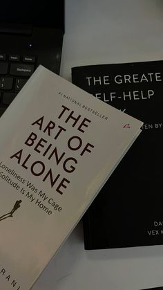 two books sitting on top of a desk next to a laptop computer and keyboard,