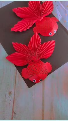 three red paper fish sitting on top of a table