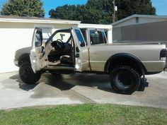 a tan truck parked in front of a house with its door open and the driver's seat up