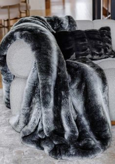 a couch covered in grey fur sitting on top of a floor