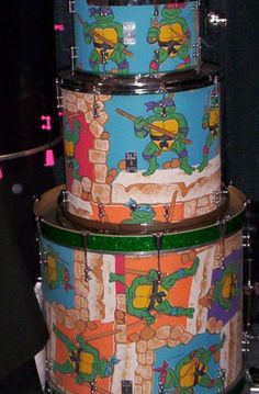 three drum sets with teenage mutant designs on them, all stacked up and ready to be played