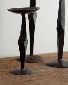 two metal candlesticks sitting on top of a wooden table next to each other