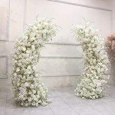 two white flowers are arranged in the shape of an o - shaped arch on display