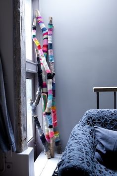 a bed sitting next to a window covered in colorful blankets and scarves on it