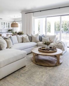 a living room filled with white furniture and lots of pillows on top of the couches